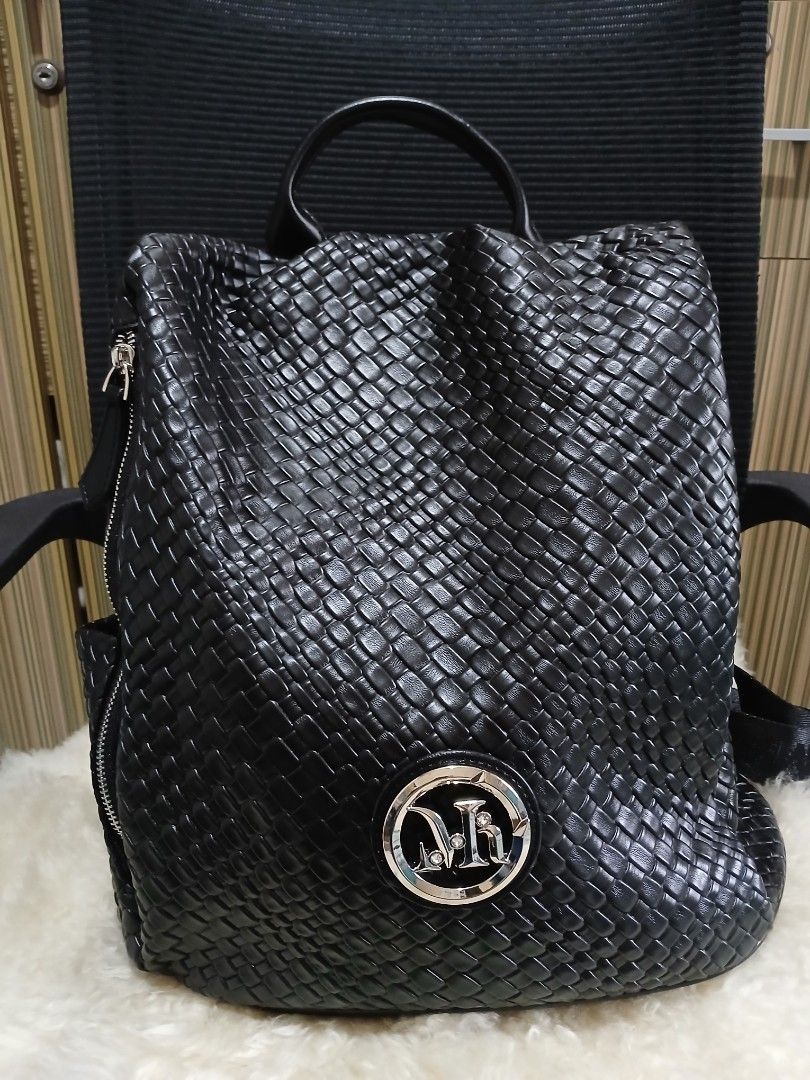 Black Woven Leather Backpack with Branded Straps (Category: Backpacks) located in Taguig. Submitted by demsclosetph (Listing ID 1470795149, Image 1). Description: - Color/Material: Black woven faux leather - Hardware: Silver-tone with crystal-accented round front logo plate - Straps: Adjustable fabric straps with stylish printed lettering - Pockets: Secure zippered main compartment and exterior zip pocket - Convenience: Top grab handle included -