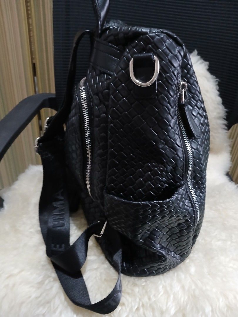 Black Woven Leather Backpack with Branded Straps (Category: Backpacks) located in Taguig. Submitted by demsclosetph (Listing ID 1470795149, Image 3). Description: - Color/Material: Black woven faux leather - Hardware: Silver-tone with crystal-accented round front logo plate - Straps: Adjustable fabric straps with stylish printed lettering - Pockets: Secure zippered main compartment and exterior zip pocket - Convenience: Top grab handle included -