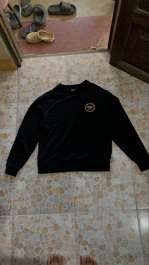 Boy London Black Sweatshirt with Gold Eagle Logo (Category: Coats, Jackets and Outerwear) located in Canaman. Submitted by marc.elizar (Listing ID 1470768092, Image 1). Description: - Brand: Boy London - Color: Solid black - Size: Medium (M) - Design: Gold embroidered circular chain logo with eagle and lettering on chest - Style: Classic crewneck pullover with ribbed cuffs and hem - Interior: Soft fleece lining for extra warmth and comfort - Cond