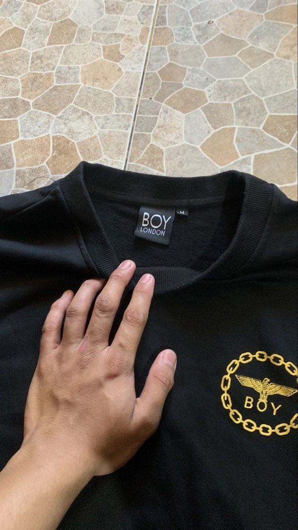Boy London Black Sweatshirt with Gold Eagle Logo (Category: Coats, Jackets and Outerwear) located in Canaman. Submitted by marc.elizar (Listing ID 1470768092, Image 3). Description: - Brand: Boy London - Color: Solid black - Size: Medium (M) - Design: Gold embroidered circular chain logo with eagle and lettering on chest - Style: Classic crewneck pullover with ribbed cuffs and hem - Interior: Soft fleece lining for extra warmth and comfort - Cond