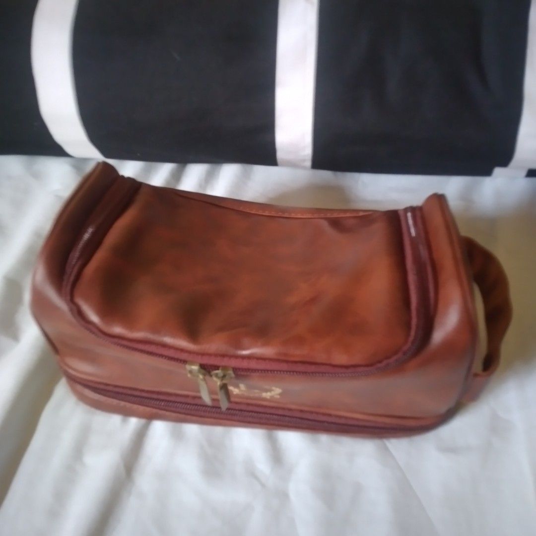 Brown Leather Toiletry Bag with Hanging Hook (Category: Luxury Bags & Wallets) located in Manila. Submitted by howiebowie19_77 (Listing ID 1470779160, Image 2). Description: - Color: Brown faux leather with elegant gold 'L' crest logo - Convenient top handle for easy carrying - Built-in metal hook for hanging in bathrooms or closets while traveling - Multiple internal zippered pockets for neat organization of skincare, cosmetics, or shaving gear 