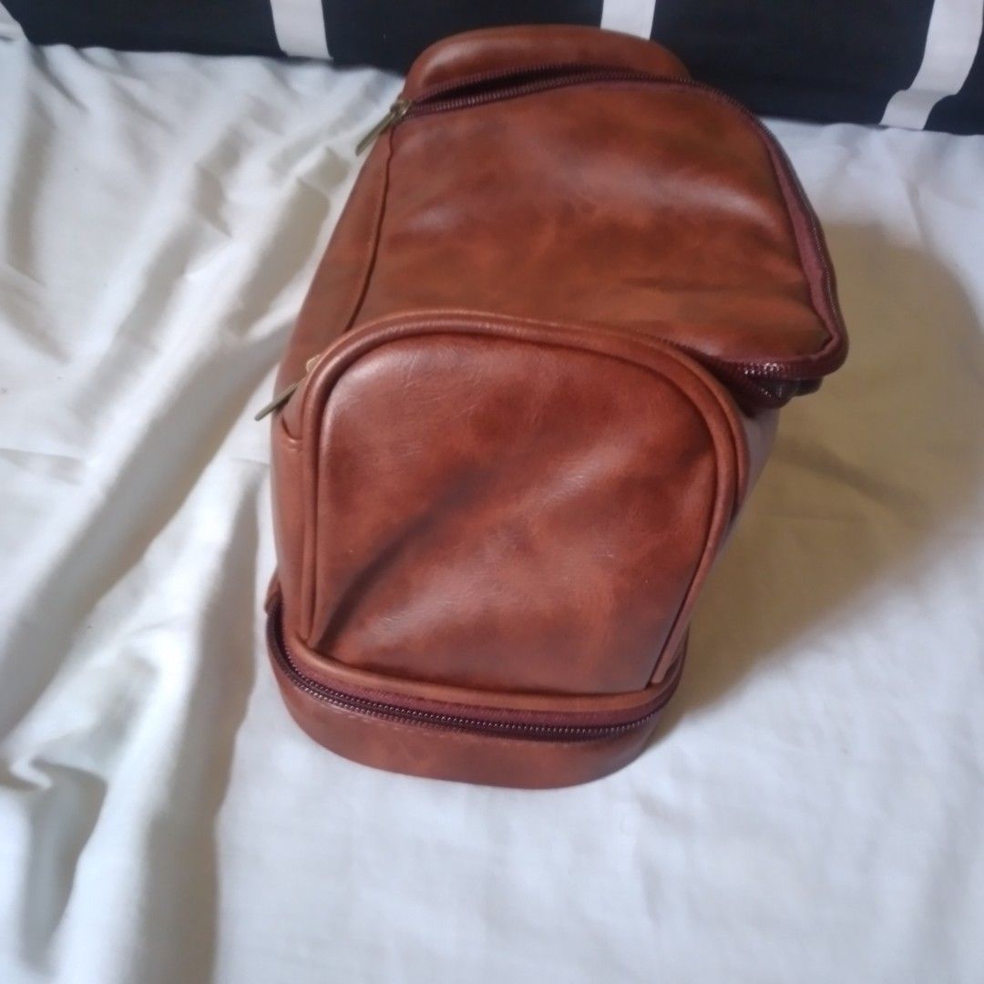 Brown Leather Toiletry Bag with Hanging Hook (Category: Luxury Bags & Wallets) located in Manila. Submitted by howiebowie19_77 (Listing ID 1470779160, Image 3). Description: - Color: Brown faux leather with elegant gold 'L' crest logo - Convenient top handle for easy carrying - Built-in metal hook for hanging in bathrooms or closets while traveling - Multiple internal zippered pockets for neat organization of skincare, cosmetics, or shaving gear 