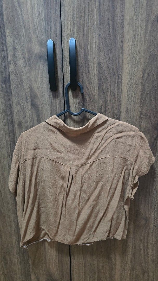 Brown short sleeve button up collared cropped shirt (Category: Shirts) located in Manila. Submitted by stuff.gaming (Listing ID 1470807048, Image 3). Description: - Color: Brown - Cut: Cropped with classic collar - Sleeves: Short sleeves - Details: Light brown front buttons, plain back with yoke seam - Material: Soft textured fabric - Condition: Clean and ready to wear - Styling: Perfect to pair with high-waisted jeans or skirts Price still negot