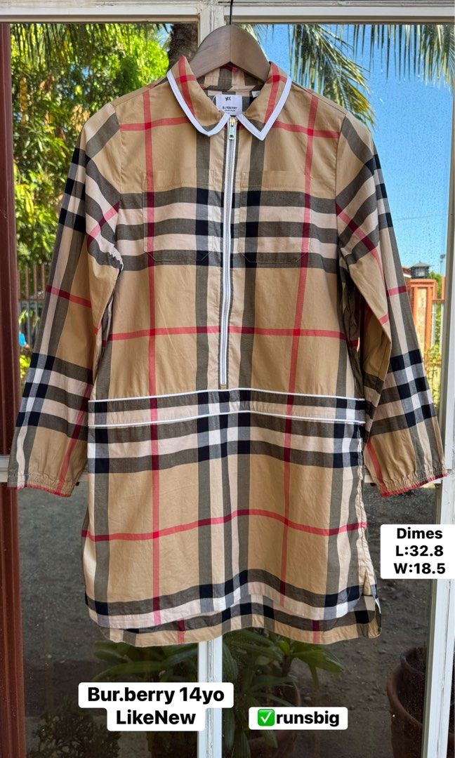 Burberry Check Quarter Zip Tunic Top 14yo (Category: Luxury Apparel) located in Pozorrubio. Submitted by izaykite2g (Listing ID 1470772035, Image 1). Description: - Iconic classic Burberry check pattern in beige, red, and black - Quarter-zip front closure with stylish white trim on collar and hem - Two convenient front chest pockets - Long sleeves with comfortable elastic cuffs - Size: Fits like a youth size 14 years old - Measurements: Length 32