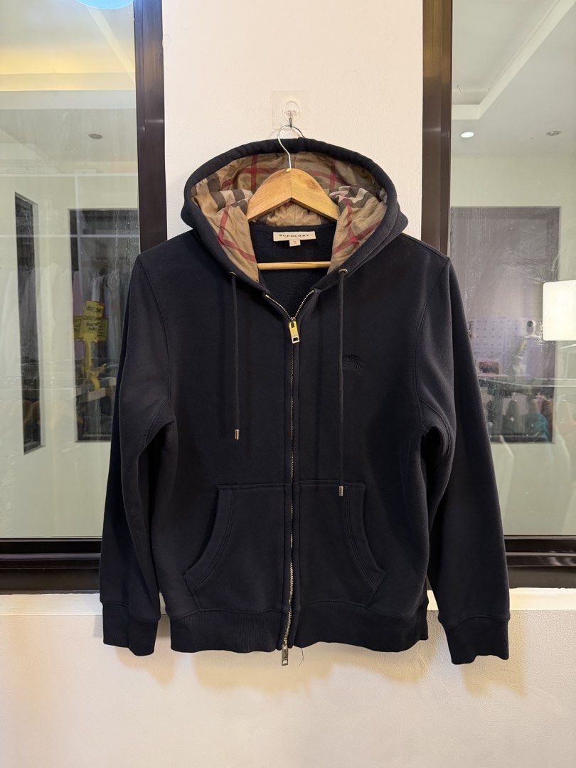 Burberry Full-Zip Hooded Sweatshirt (Category: Coats, Jackets and Outerwear) located in Paranaque City. Submitted by preluxeshop_ph (Listing ID 1470818171, Image 2). Description: Brand: Burberry London •Style: Full-Zip Hooded Sweatshirt / Zip Hoodie •Color: Black with signature vintage check lining inside the hood •Design Features: Full front zip closure with gold-tone hardware, drawstring hood with check pattern interior, front split kangaroo po