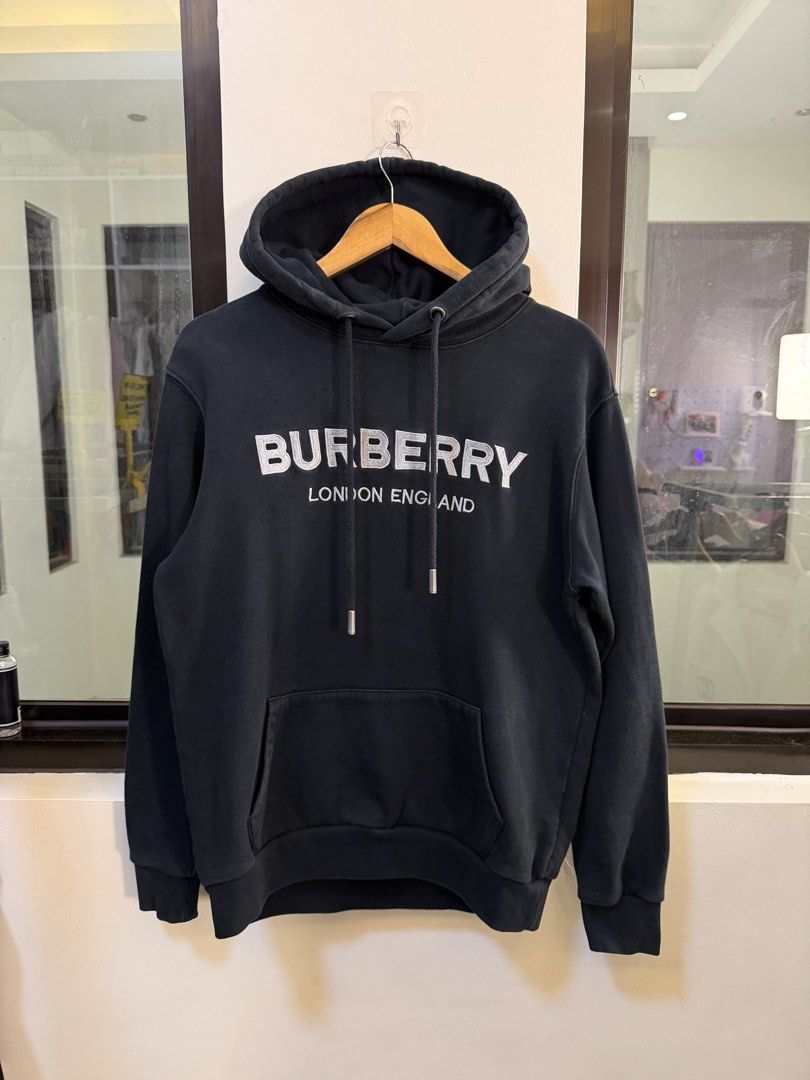 Burberry Pullover Hoodie (Category: Coats, Jackets and Outerwear) located in Paranaque City. Submitted by preluxeshop_ph (Listing ID 1470813527, Image 2). Description: Brand: Burberry London England -Style: Pullover Hoodie / Hooded Sweatshirt -Color: Dark Navy Blue -Design Features: Printed white Burberry London England logo across the chest, Thomas Bear motif graphic patch on the back, drawstring hood, and front kangaroo pocket -Material Composi