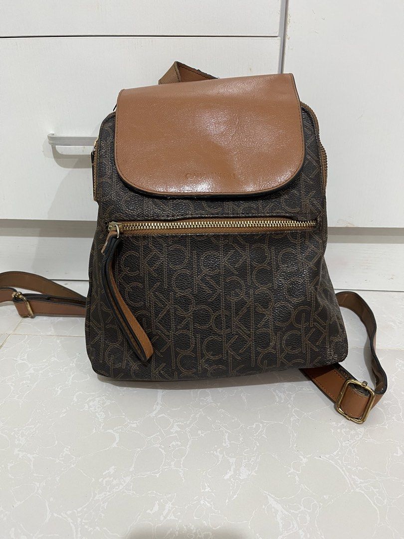 Calvin Klein Monogram Brown Tan Backpack (Category: Backpacks) located in Cainta. Submitted by rizeru_18 (Listing ID 1470751334, Image 1). Description: - Calvin Klein backpack in stylish brown monogram print - Dual security: flap top with magnetic snap closure plus a main zip compartment - Extra storage: convenient front zip pocket and exterior back zip pocket - Comfortable wear: adjustable shoulder straps and top grab handle - Organized interior