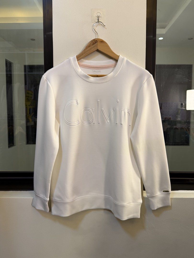 Calvin Klein Performance Long-Sleeve Crewneck Sweatshirt (Category: Coats, Jackets and Outerwear) located in Paranaque City. Submitted by preluxeshop_ph (Listing ID 1470814183, Image 2). Description: Brand: Calvin Klein Performance (Quick Dry line) •Style: Long-Sleeve Crewneck Sweatshirt / Pullover •Color: White with subtle pink inner neck taping •Design Features: Embossed tonal “Calvin” logo lettering across the chest, crew neckline, and ribbed 