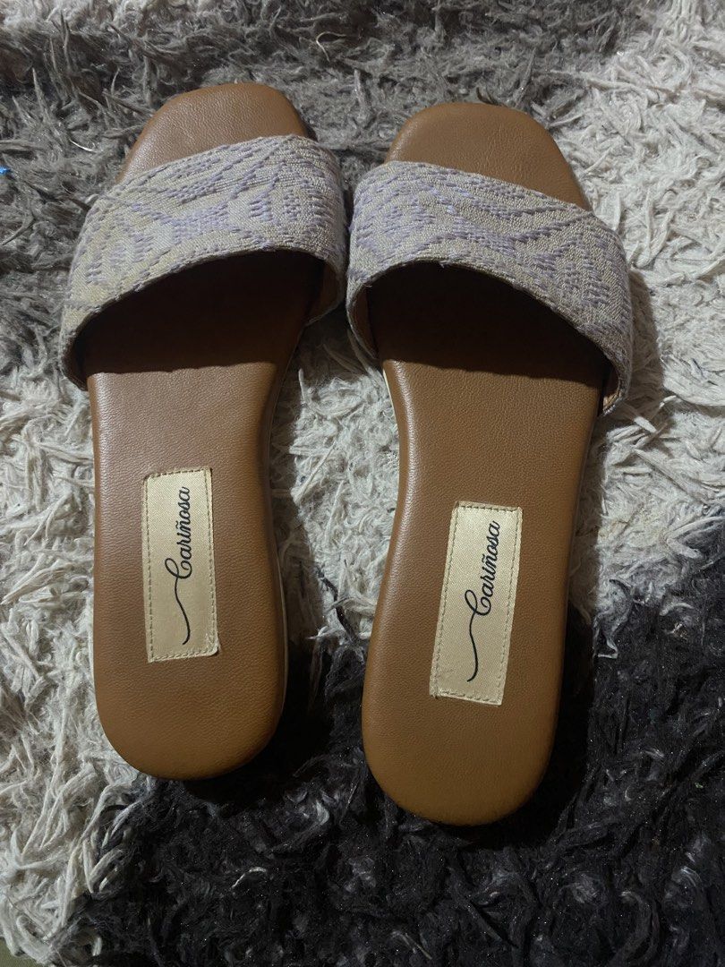 Cariñosa Purple Woven Pattern Slide Sandals Size 6 (Category: Flats & Sandals) located in Caloocan City. Submitted by remythrift (Listing ID 1470754989, Image 1). Description: - Brand: Cariñosa - Style: Slip-on sandals - Color: Tan and purple - Size: 6 (stamped on sole) - Upper: Textured woven pattern strap - Insole: Brown with stitched brand label - Sole: Low flat heel with textured rubber traction - Condition: Good, with slight wear at the toe 