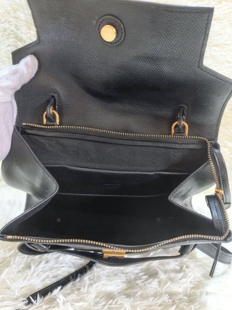Celine Black Leather Handbag with Strap (Category: Luxury Bags & Wallets) located in Tacloban City. Submitted by thead.declutters (Listing ID 1470880079, Image 2). Description: - Material: Premium black textured leather with luxury gold-tone hardware - Versatility: Includes a sturdy top handle and a removable shoulder strap with clasp closure - Closure & Security: Flap top with a secure magnetic snap button - Pockets: Convenient exterior back zip