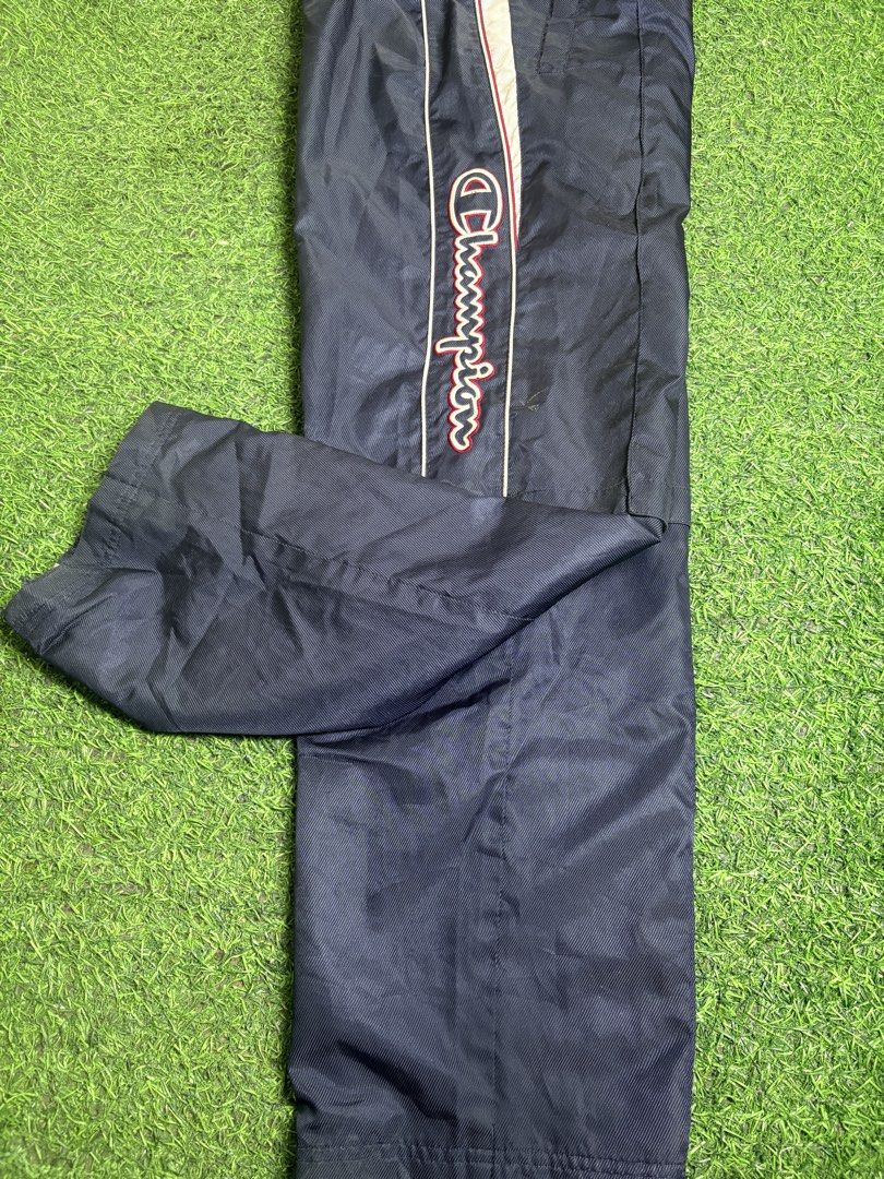 Champion Track Pant (Category: Trousers) located in Manila. Submitted by josh2295 (Listing ID 1470763547, Image 2). Description: vintage navy blue Champion nylon windbreaker track pants featuring a side logo script and red-and-white piping detail. W: 30- 34 L:40 LH: 9.