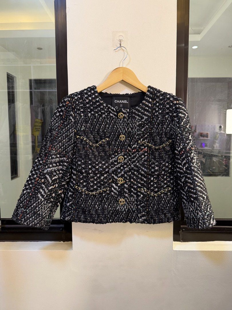 CHANEL Cropped Tweed Jacket (Category: Coats, Jackets and Outerwear) located in Paranaque City. Submitted by preluxeshop_ph (Listing ID 1470802619, Image 2). Description: Brand: CHANEL -Style: Cropped Tweed Jacket / Collarless Boxy Jacket -Color/Pattern: Black and white multi-tone chevron tweed weave with subtle accent threads -Design Features: Collarless neckline, gold-tone CC logo buttons down the front, chain-trimmed front accent pockets, and 