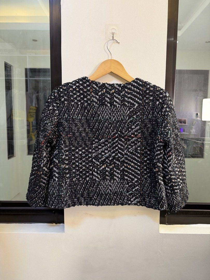 CHANEL Cropped Tweed Jacket (Category: Coats, Jackets and Outerwear) located in Paranaque City. Submitted by preluxeshop_ph (Listing ID 1470802619, Image 3). Description: Brand: CHANEL -Style: Cropped Tweed Jacket / Collarless Boxy Jacket -Color/Pattern: Black and white multi-tone chevron tweed weave with subtle accent threads -Design Features: Collarless neckline, gold-tone CC logo buttons down the front, chain-trimmed front accent pockets, and 