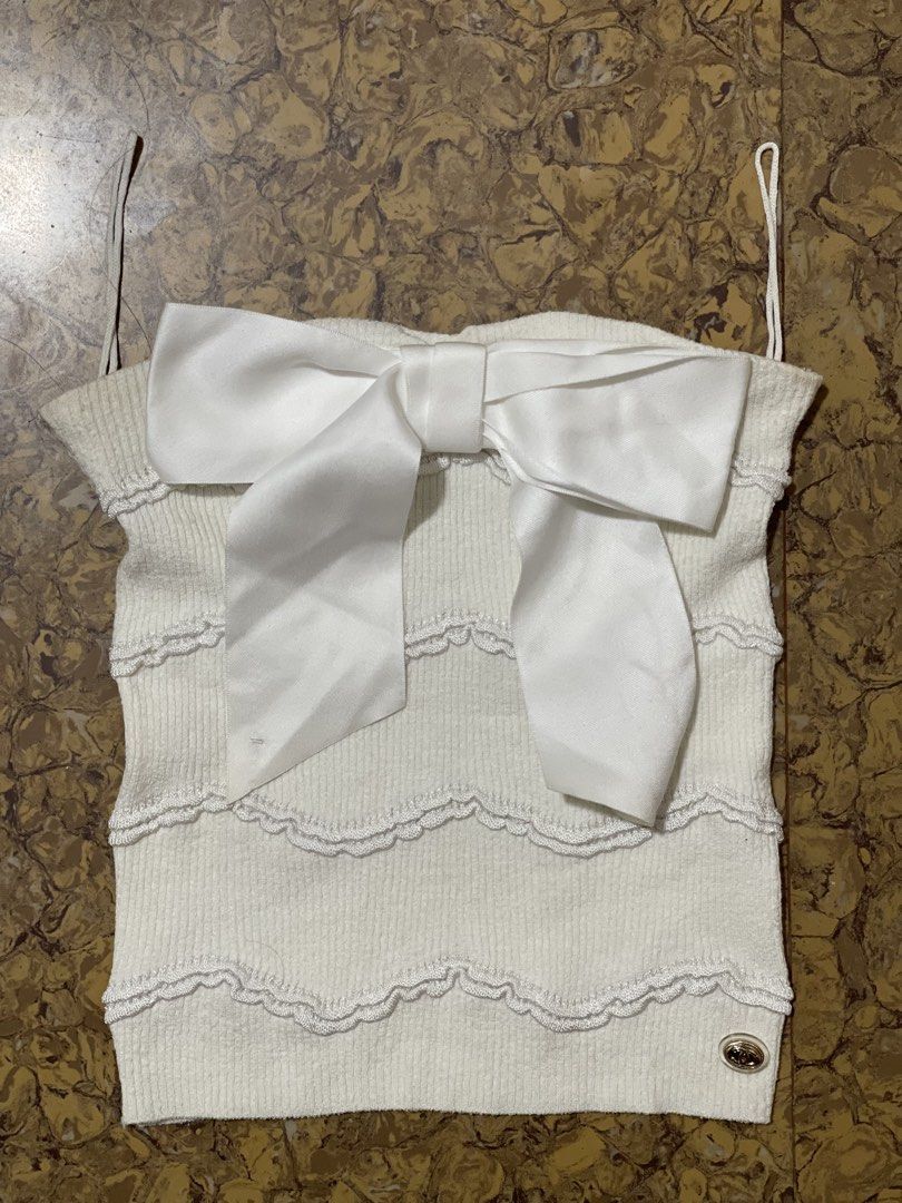 Chanel white cotton knit top (Category: Luxury Apparel) located in Marikina City. Submitted by joshuaades21107 (Listing ID 1470865020, Image 1). Description: Chanel white cotton knit top featuring a prominent satin bow and a small metal CC logo charm (style/reference code P70342 / P70342K10011, size 36) White knit sleeveless/strap top with wavy/ribbed pattern details, a large white satin bow on the front, and a CC logo emblem at the bottom corner