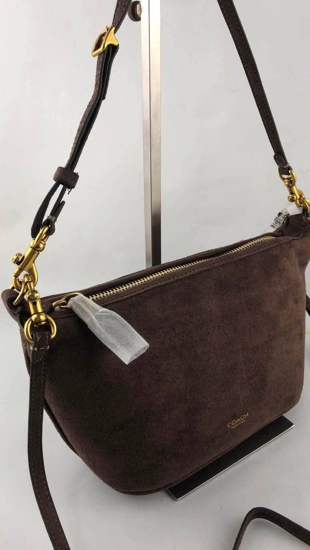 Coach Brown Suede Shoulder Bag (Category: Luxury Bags & Wallets) located in Benito Soliven. Submitted by angelgumta83832 (Listing ID 1470800409, Image 1). Description: - Authentic Coach shoulder bag in rich dark brown suede - Elegant gold-tone hardware and secure top zip closure - Adjustable leather strap equipped with stylish dog leash clasps - Subtle Coach New York gold logo stamped near the base - Soft texture with clean lines, perfect for eve