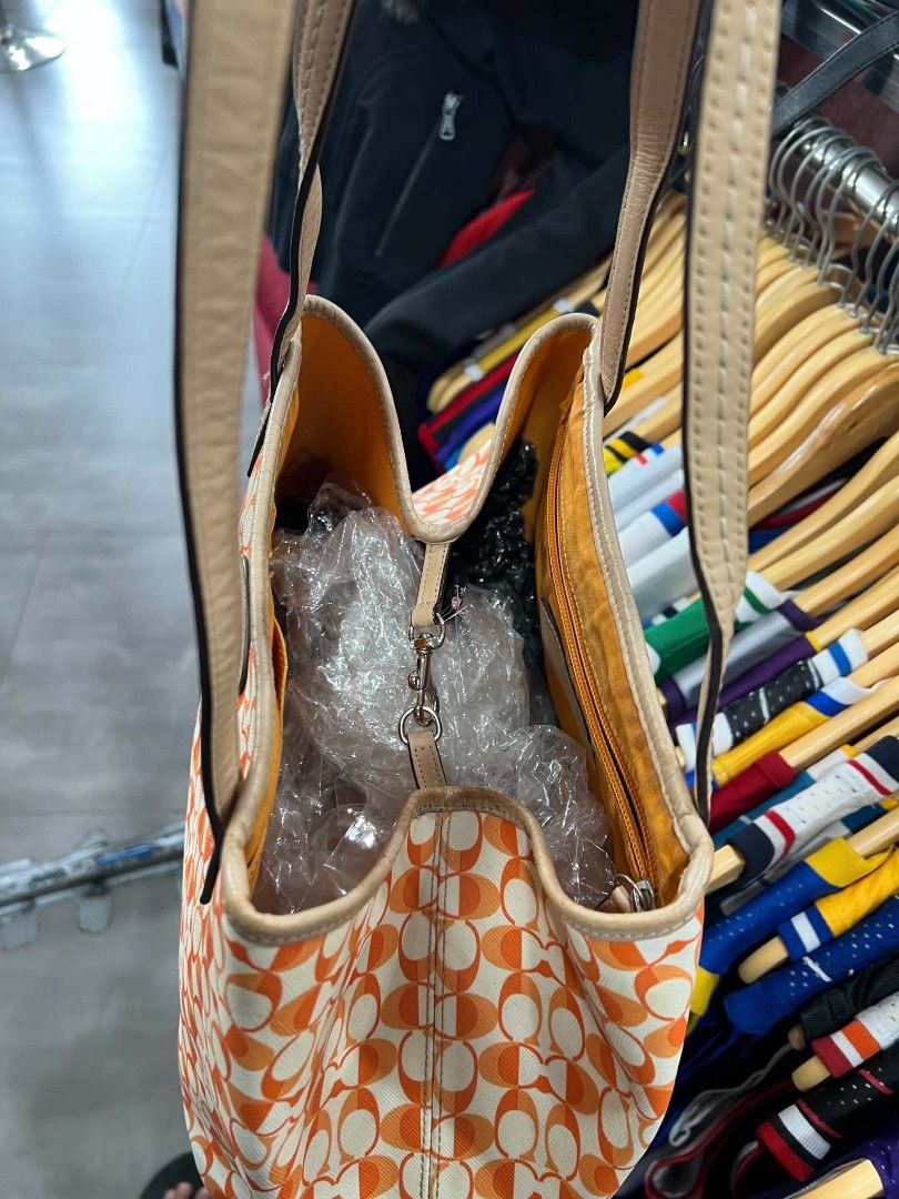 Coach Orange Monogram Tote Bag (Category: Luxury Bags & Wallets) located in Urdaneta. Submitted by jayceegarage (Listing ID 1470882622, Image 3). Description: - Authentic Coach tote bag - Eye-catching orange and white monogram pattern - Premium leather handles and front oval brand plaque - Vibrant yellow fabric interior lining - Interior zipper pocket for secure storage - Creed patch with style number: D1432-F23005 - Comfortable double handle dro