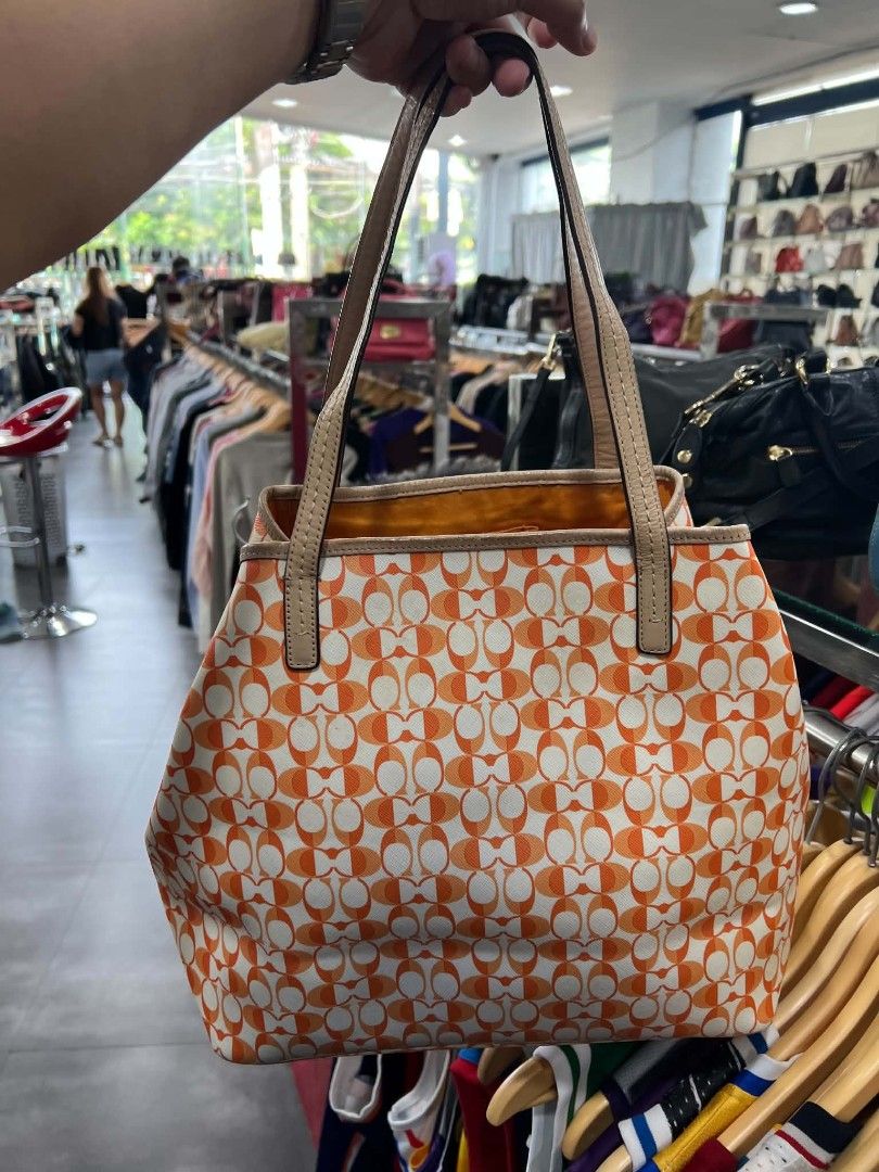 Coach Orange Monogram Tote Bag (Category: Luxury Bags & Wallets) located in Urdaneta. Submitted by jayceegarage (Listing ID 1470882622, Image 2). Description: - Authentic Coach tote bag - Eye-catching orange and white monogram pattern - Premium leather handles and front oval brand plaque - Vibrant yellow fabric interior lining - Interior zipper pocket for secure storage - Creed patch with style number: D1432-F23005 - Comfortable double handle dro