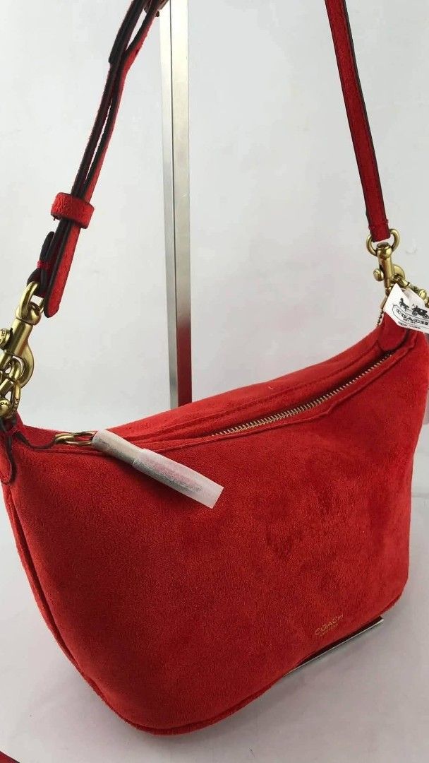 Coach Red Suede Shoulder Bag (Category: Luxury Bags & Wallets) located in Benito Soliven. Submitted by angelgumta83832 (Listing ID 1470800739, Image 1). Description: - Brand: Coach - Material: Soft red suede with leather strap - Hardware: Gold-tone - Closure: Zip top with protective wrapping still attached - Details: Debossed Coach logo on the front, adjustable strap with metal clips - Fit: Compact size, comfortable under-arm shoulder bag - Condi