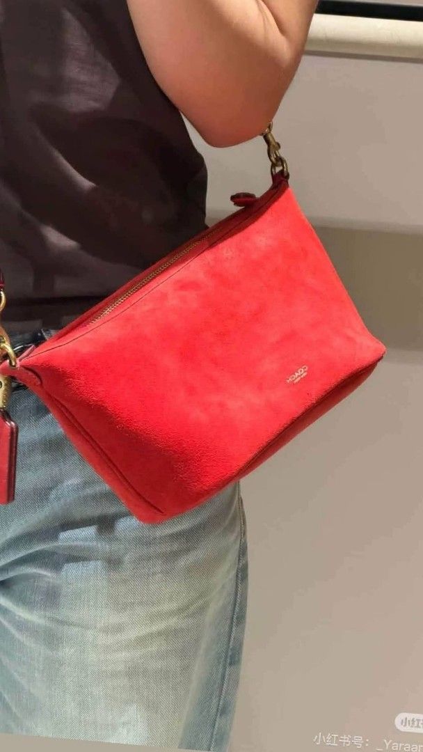 Coach Red Suede Shoulder Bag (Category: Luxury Bags & Wallets) located in Benito Soliven. Submitted by angelgumta83832 (Listing ID 1470800739, Image 2). Description: - Brand: Coach - Material: Soft red suede with leather strap - Hardware: Gold-tone - Closure: Zip top with protective wrapping still attached - Details: Debossed Coach logo on the front, adjustable strap with metal clips - Fit: Compact size, comfortable under-arm shoulder bag - Condi