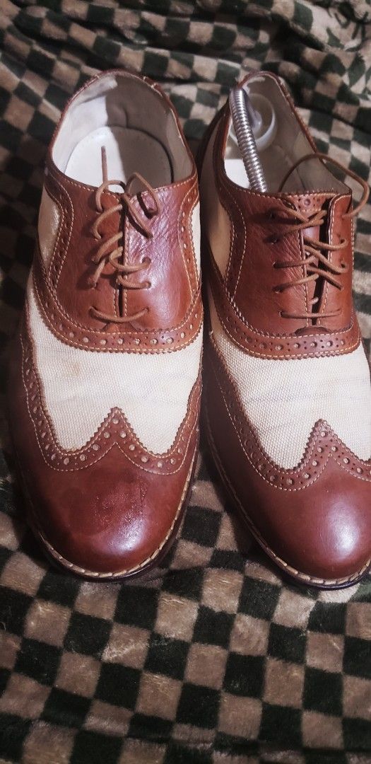 Cole Haan Two-Tone Wingtip Brogues (Category: Dress Shoes) located in Marikina City. Submitted by racoon143 (Listing ID 1470868893, Image 1). Description: - Brand: Cole Haan - Style: Wingtip dress shoes with traditional brogue detailing - Material: Two-tone design with brown leather and off-white canvas panels - Features: Lace-up closure with thin brown laces, branded leather insoles, and dark brown stacked heels - Condition: Good pre-owned condi