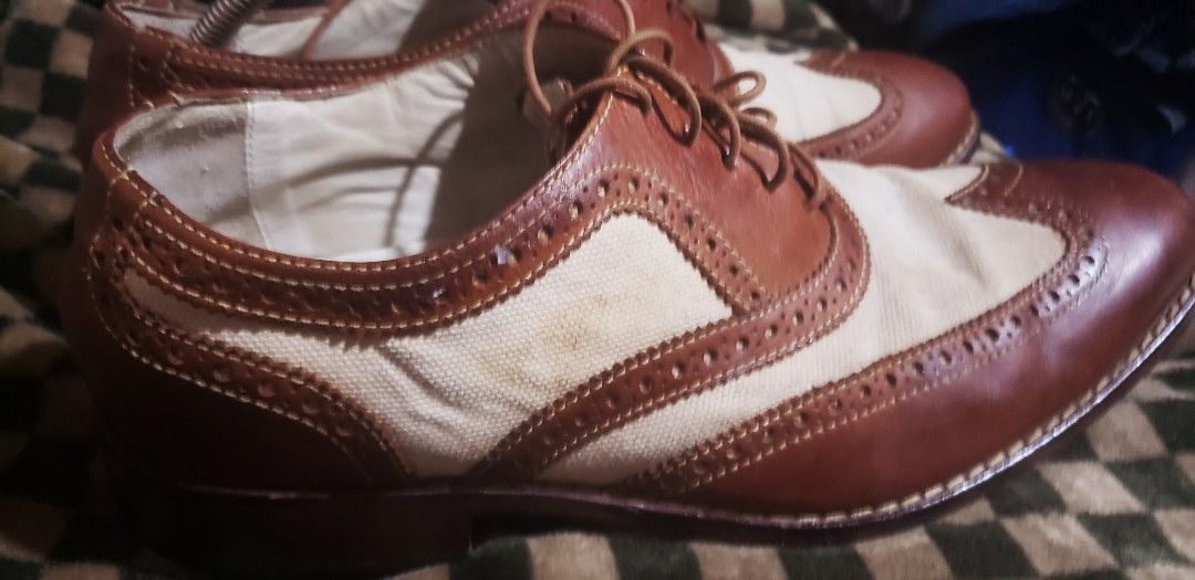 Cole Haan Two-Tone Wingtip Brogues (Category: Dress Shoes) located in Marikina City. Submitted by racoon143 (Listing ID 1470868893, Image 3). Description: - Brand: Cole Haan - Style: Wingtip dress shoes with traditional brogue detailing - Material: Two-tone design with brown leather and off-white canvas panels - Features: Lace-up closure with thin brown laces, branded leather insoles, and dark brown stacked heels - Condition: Good pre-owned condi