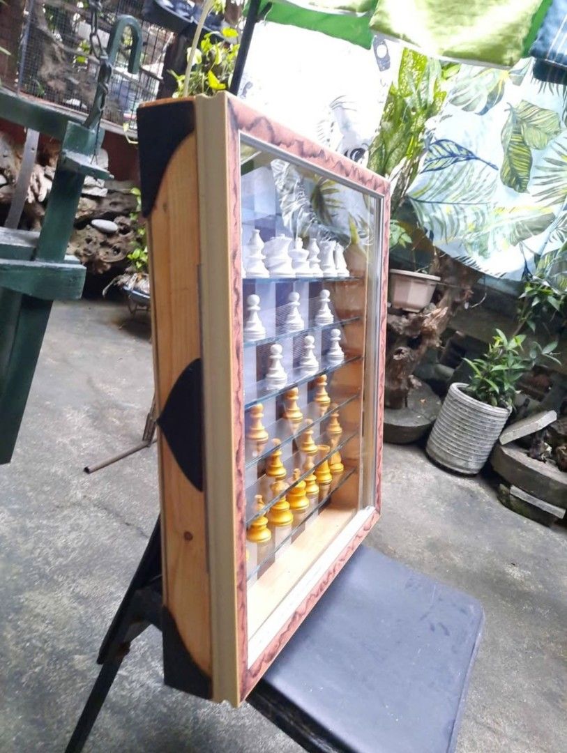 Custom-Made Big Wall Hanging Chess Set With Glass Display Case (Category: Board Games & Puzzles) located in Marilao. Submitted by mariealeiah (Listing ID 1470757872, Image 2). Description: - Unique wooden chess set with a glass-front display case for wall mounting - Features an alternating brown and silver board with glass shelves - Includes stunning white and yellow-gold chess pieces - Designed with a decorative brown patterned frame, side hinge