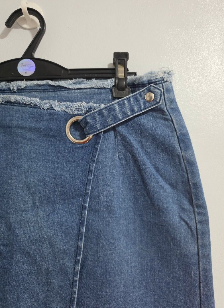 Denim Wrap Skirt with Ring Detail (Category: Skirts) located in Paranaque City. Submitted by franinnashop (Listing ID 1470795449, Image 2). Description: Declutter issue last photo - Style: Blue denim wrap skirt with a trendy raw frayed hem and side zipper closure - Details: Features a decorative waist strap with a silver-tone ring and snap button - Measurements: Waist 30-32 inches | Hips 38 inches | Length 15.5 inches - Condition: Noticeable fadi