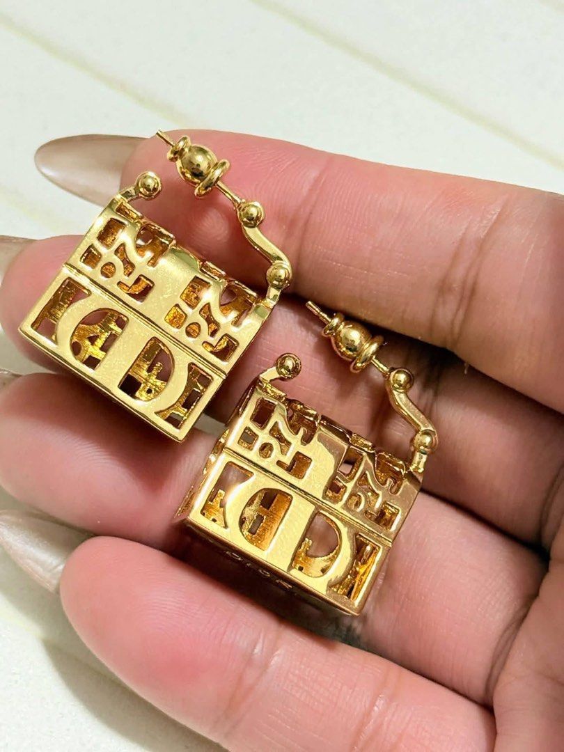 Dior Gold Cube Earrings Made in Italy (Category: Earrings) located in Lopez. Submitted by thrift.ni.roms22 (Listing ID 1470743934, Image 2). Description: - gold-tone Dior cube earrings - Chic cutout monogram design - Marked DIOR and MADE IN ITALY on the base - Secure post backing with decorative ball hardware - Polished finish with minimal micro-scratches from storage - Perfect luxury accessory to elevate your everyday look.