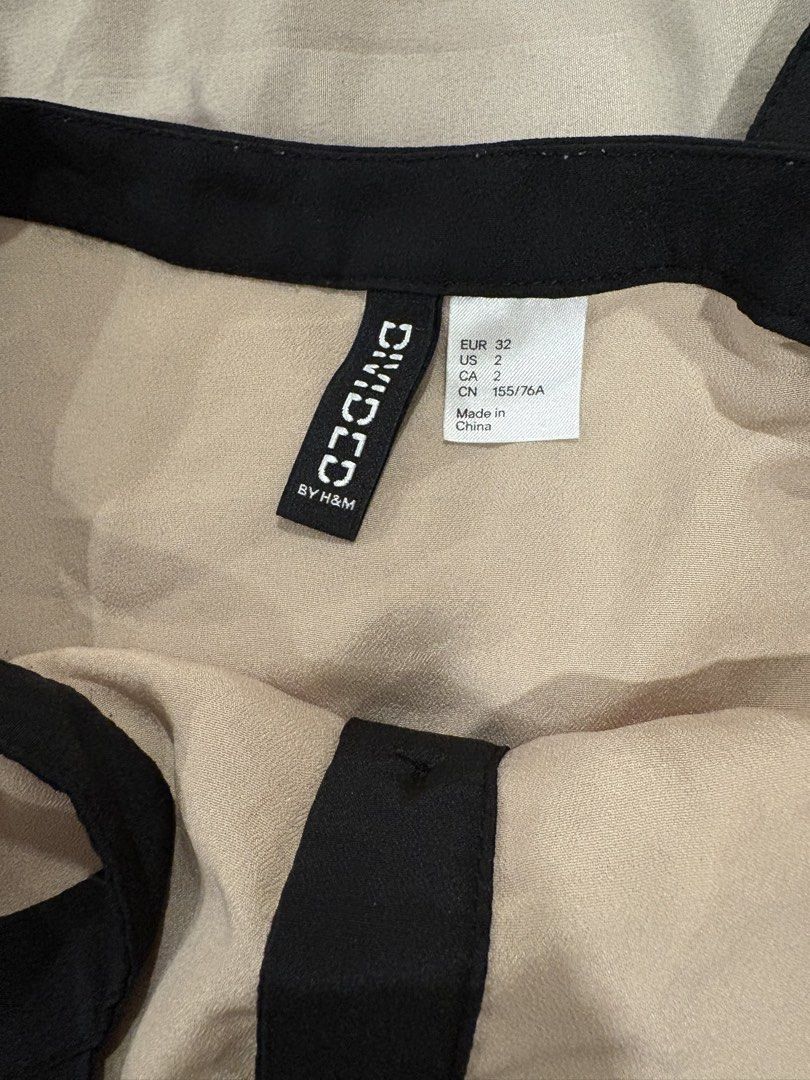 Divided by H&M Beige Black Button Tank Top Size 2 (Category: Sleeveless) located in Pasig City. Submitted by fashionforward16 (Listing ID 1470821060, Image 2). Description: - Brand: Divided by H&M - Style: Sleeveless tank top with full-length front button placket - Color: Beige with contrasting black straps and trim - Material: Lightweight slightly sheer fabric .
