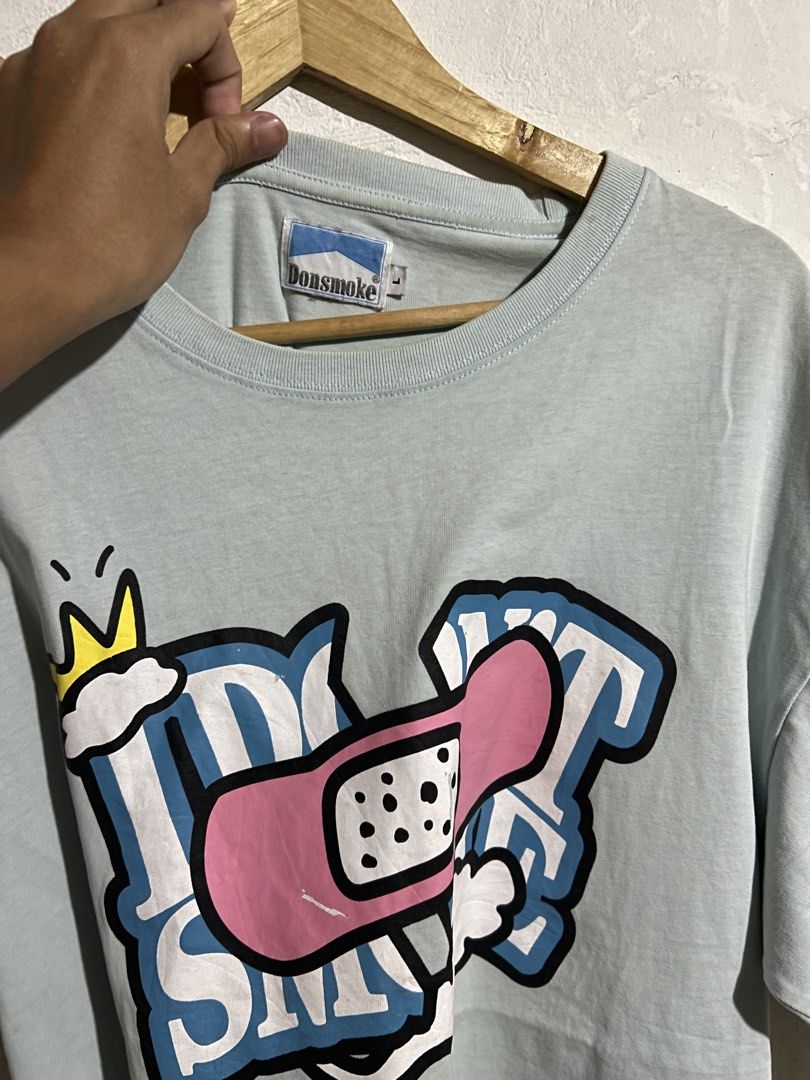 Donsmoke Graphic Tee Light Blue Size L (Category: Tshirts & Polo Shirts ) located in Manila. Submitted by romnick907 (Listing ID 1470819320, Image 2). Description: - Brand: Donsmoke - Color: Light Blue - Size: Large (tag at collar and inner hem) - Design: Large front graphic featuring a crown, cloud, and pink adhesive bandage motif - Material: Clean, high-quality cotton with vibrant screen-print - Condition: Excellent/Ready to wear.