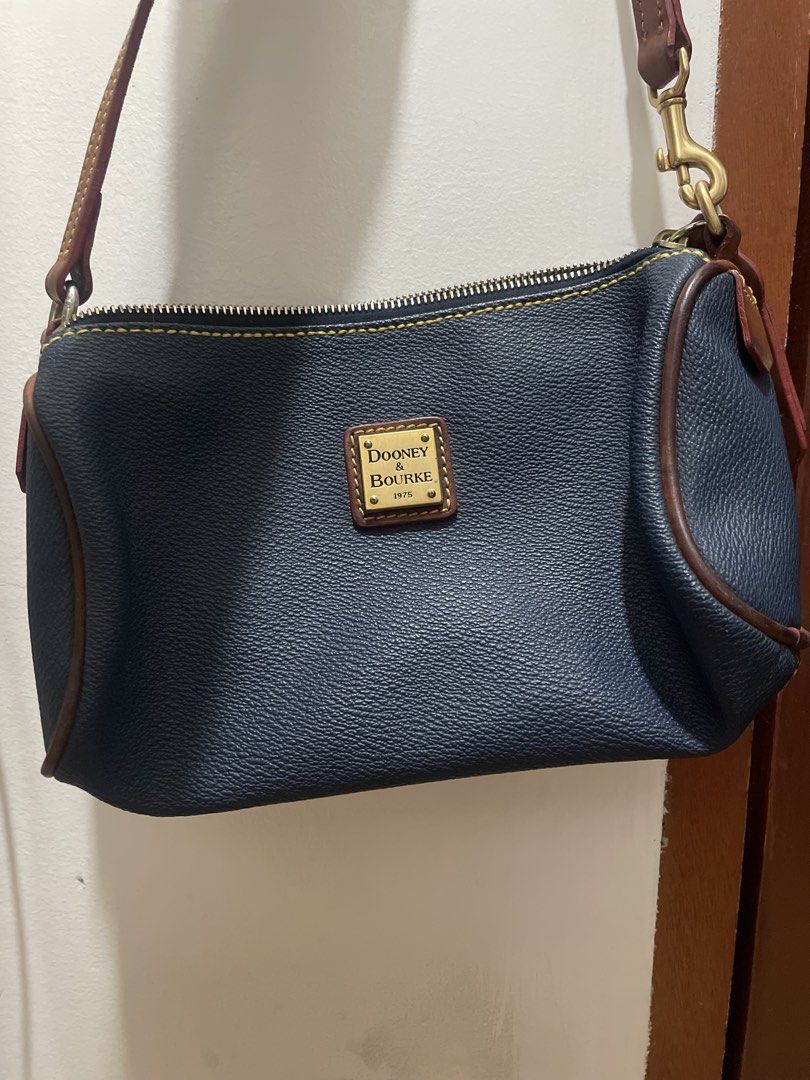 Dooney & Bourke Navy Leather Shoulder Bag (Category: Luxury Bags & Wallets) located in Davao. Submitted by newowl_777 (Listing ID 1470845248, Image 1). Description: - Brand: Dooney & Bourke - Material: Navy blue pebbled leather with brown leather trim - Design details: Contrast yellow stitching and gold-tone metal hardware with lobster clasps - Closure: Secure zip top closure - Branding: Small rectangular gold logo plaque stamped with 1975 on the