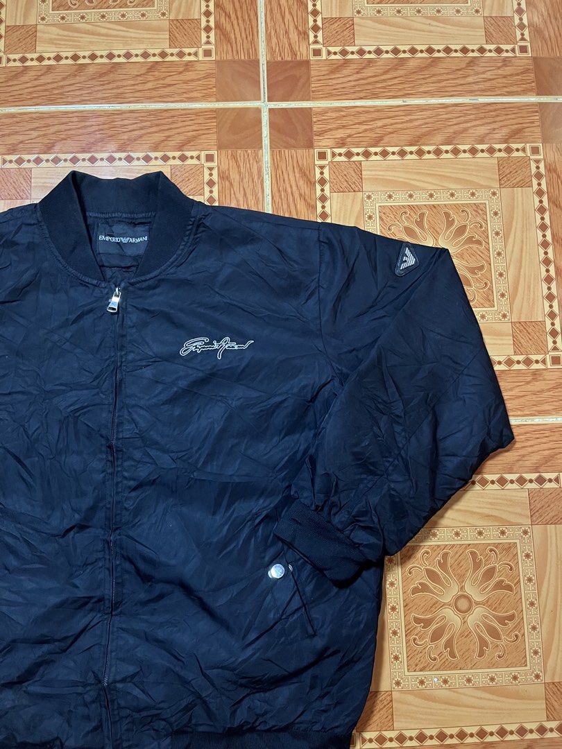 Emporio Armani Black Bomber Jacket (Category: Coats, Jackets and Outerwear) located in Kidapawan. Submitted by azythrift (Listing ID 1470822860, Image 2). Description: - Authentic Emporio Armani black bomber jacket 23x26 unisex - Classic ribbed collar, cuffs, and hem for a snug fit - Secure front zip closure with convenient waist snap-button pockets - Stylish embroidered script logo on the chest - Signature small eagle patch on the left sleeve - 