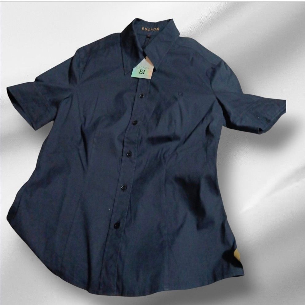 Escada Dark Blue Button-Down Shirt (Category: Shirts) located in Paranaque City. Submitted by calm_youngstore7 (Listing ID 1470788669, Image 1). Description: LAST PIECE SALE! - Brand: Escada - Color: Classic Dark Blue - Condition: Brand new with tags attached - Design: Short sleeves, front button closure, and traditional pointed collar - Detail: Subtle embroidered logo on the chest - Style: Versatile and chic, perfect for smart-casual or office w