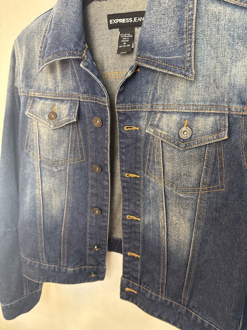 Express Jeans Women's Blue Denim Jacket (Category: Coats, Jackets and Outerwear) located in Quezon City. Submitted by dropdeadprices (Listing ID 1470778761, Image 2). Description: - Brand: Express - Style: Classic blue denim jacket - Features: Front button closure, chest pockets, classic collar, and long sleeves with buttoned cuffs - Details: Faded wash finish and adjustable button tabs at the back hem - Material: Sturdy cotton denim - Fit/Use: G
