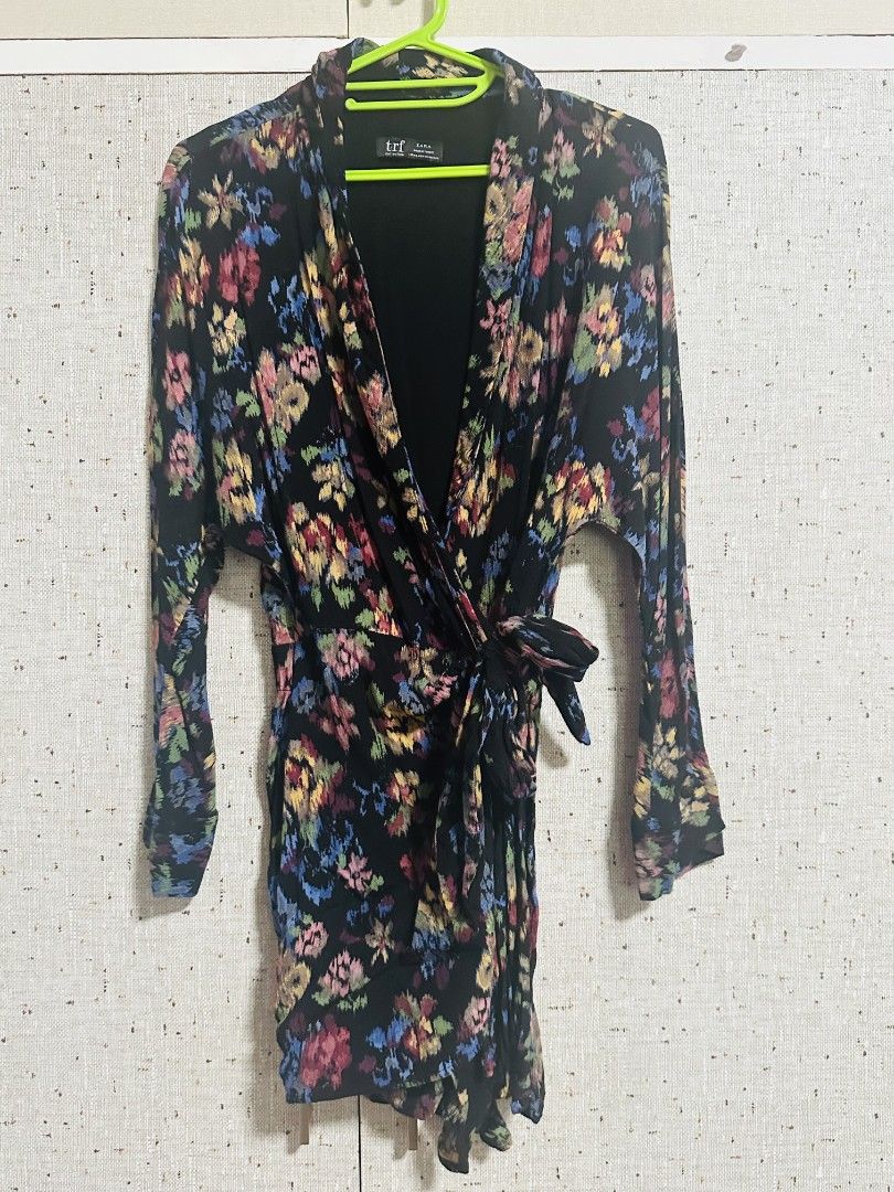 Floral Wrap Mini Romper with Long Sleeves (Category: Dresses) located in Manila. Submitted by thebestre (Listing ID 1470879391, Image 2). Description: - Color & Pattern: Black with a vibrant colourful floral print - Design: V-neck, long sleeves, and a flattering wrap style - Fit: Includes a matching fabric tie belt at the waist - Length: Short, hits above the knee - Material: Lightweight and comfortable - Styling Tip: Looks amazing paired with an