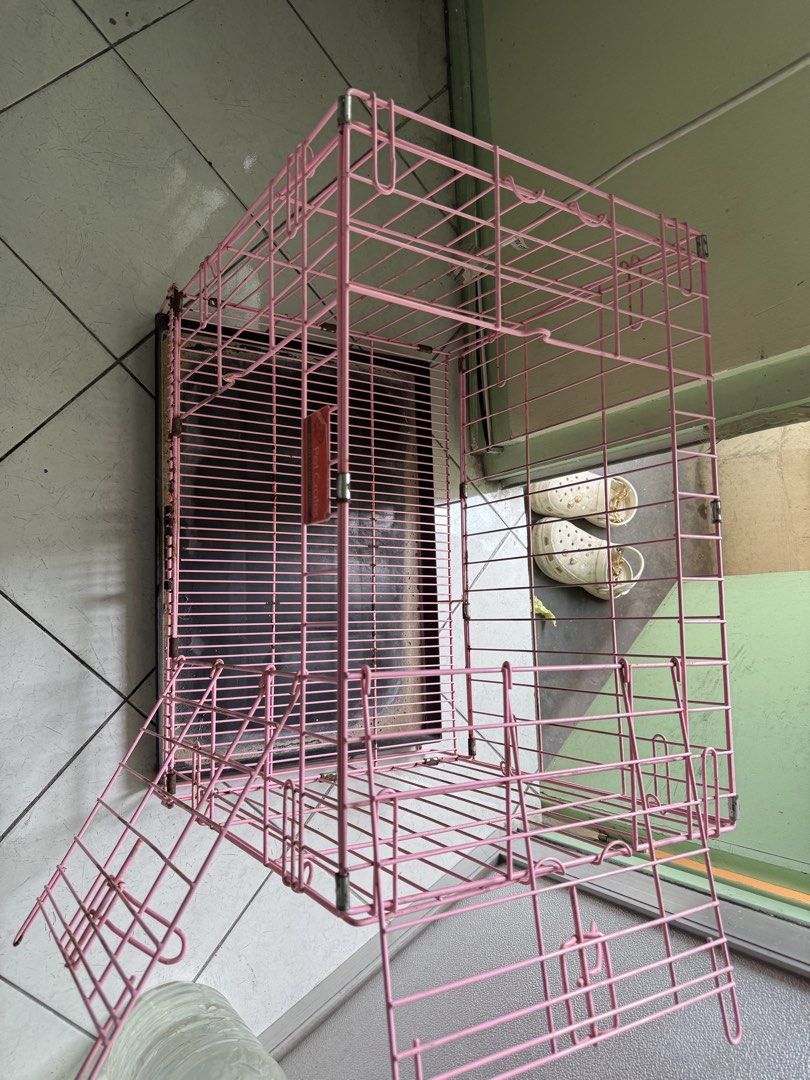 Foldable Pet Crate with Removable Tray 60x44x45 cm (Category: Storage Boxes & Baskets) located in Manila. Submitted by pasaybestfinds (Listing ID 1470758973, Image 2). Description: - Color: Pink metal wire with a removable black plastic tray - Design: Double doors with secure latches - Condition: Solid and sturdy structure with minor rust spots near hinges and corners - Portability: Easy to fold down for convenient storage and transport - Ideal f