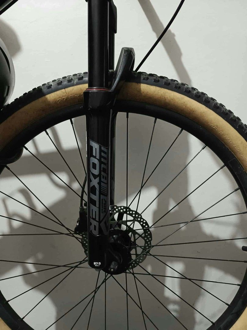 Foxter 27.5 Mountain Bike (Category: Bicycles) located in Marikina City. Submitted by wisebuytoo (Listing ID 1470823893, Image 2). Description: - Bike Model: Foxter Mountain Bike with 27.5-inch wheels - Tires: Kenda tan wall tires - Frame: Dark gray with prominent silver branding - Components: Front suspension fork, reliable disc brakes, and Charm crankset - Cockpit: Foxter stem on handlebars - Protection: Chainstay protector installed on rear fr