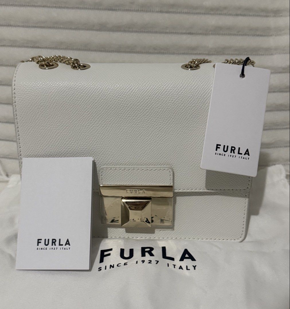 Furla Venere Crossbody MINI White Bag (Category: Cross-body Bags) located in Las Pinas. Submitted by purse.vanity (Listing ID 1470833146, Image 1). Description: - Brand: Furla - Model: Venere Crossbody MINI - Color: White - Condition: Brand new, never used, pristine condition - Material: Textured leather finish - Hardware: Gold-tone chain strap and metal push-lock closure (protective plastic film still attached) - Inclusions: Original tag, care c