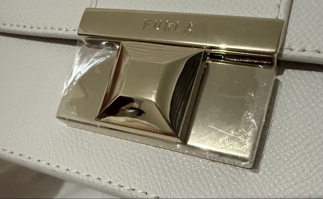 Furla Venere Crossbody MINI White Bag (Category: Cross-body Bags) located in Las Pinas. Submitted by purse.vanity (Listing ID 1470833146, Image 2). Description: - Brand: Furla - Model: Venere Crossbody MINI - Color: White - Condition: Brand new, never used, pristine condition - Material: Textured leather finish - Hardware: Gold-tone chain strap and metal push-lock closure (protective plastic film still attached) - Inclusions: Original tag, care c