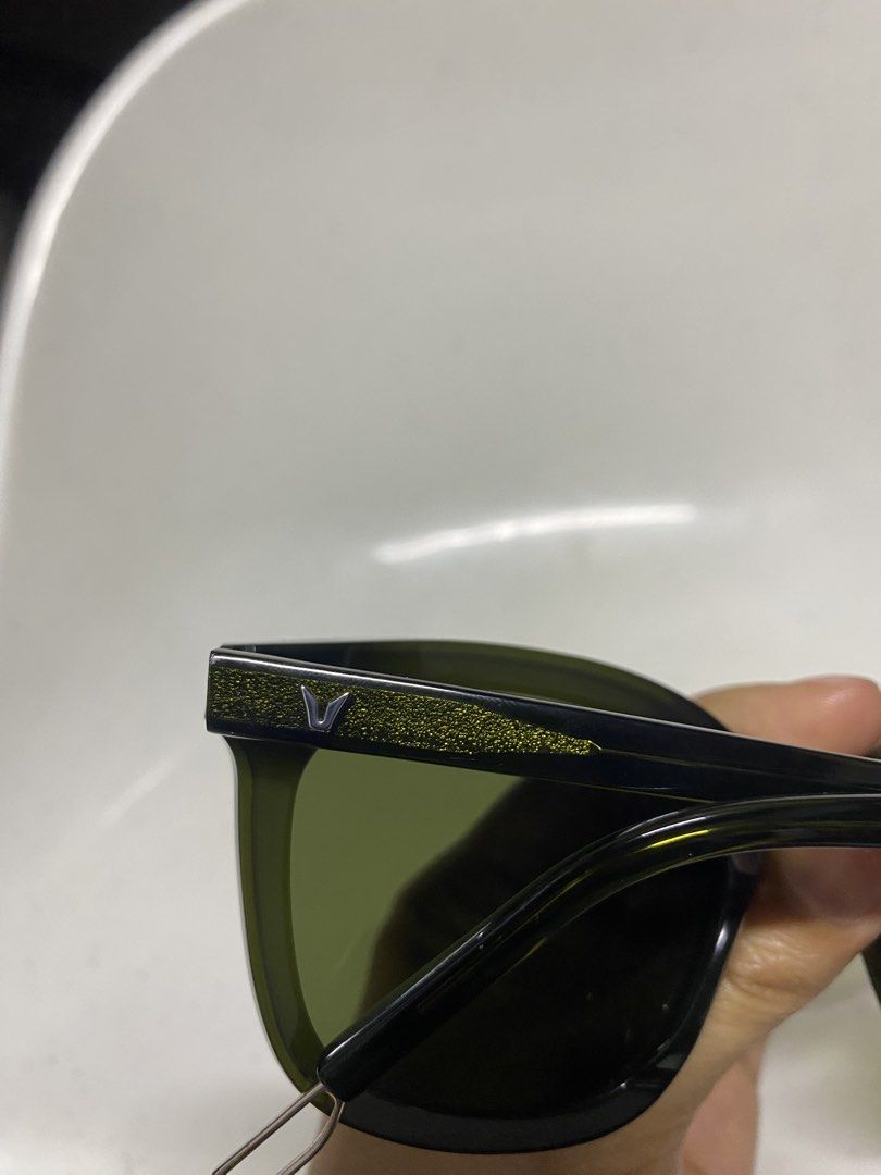 Gentle Monster Flatba Sunglasses Green Black (Category: Sunglasses & Eyewear) located in Pasacao. Submitted by wengpullar37205 (Listing ID 1470889979, Image 3). Description: - Brand: Gentle Monster Flatba - Colorway: Green and black with tinted lenses - Details: Distinctive gold glitter accents near the hinges and temple arms - Branding: Signature V logo on both sides - Frame: Trendy square shape - Special Feature: Metal loop detail at the temple