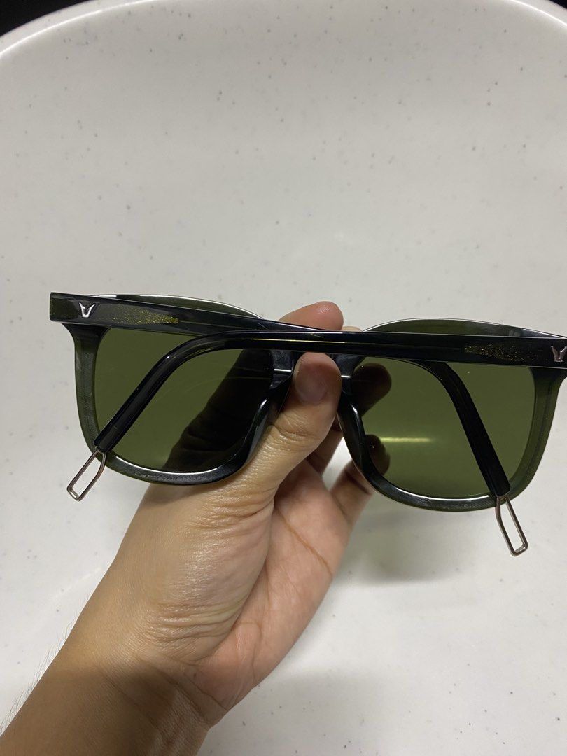 Gentle Monster Flatba Sunglasses Green Black (Category: Sunglasses & Eyewear) located in Pasacao. Submitted by wengpullar37205 (Listing ID 1470889979, Image 2). Description: - Brand: Gentle Monster Flatba - Colorway: Green and black with tinted lenses - Details: Distinctive gold glitter accents near the hinges and temple arms - Branding: Signature V logo on both sides - Frame: Trendy square shape - Special Feature: Metal loop detail at the temple