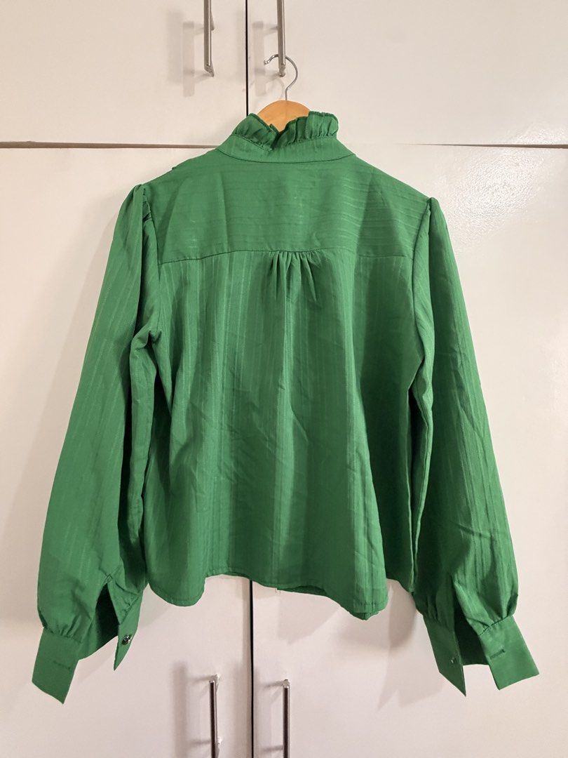 Green Ruffle Long Sleeve Button Down Blouse (Category: Longsleeves) located in Marikina City. Submitted by _bananahanaa (Listing ID 1470770349, Image 2). Description: - Color: Bright green - Design: High neck with ruffle trim and pearl-style buttons - Details: Gathered cuffs, back yoke pleating, and pleated texture - Fit: Loose and comfortable - Styling: Perfect to pair with your favorite skirts or pants.