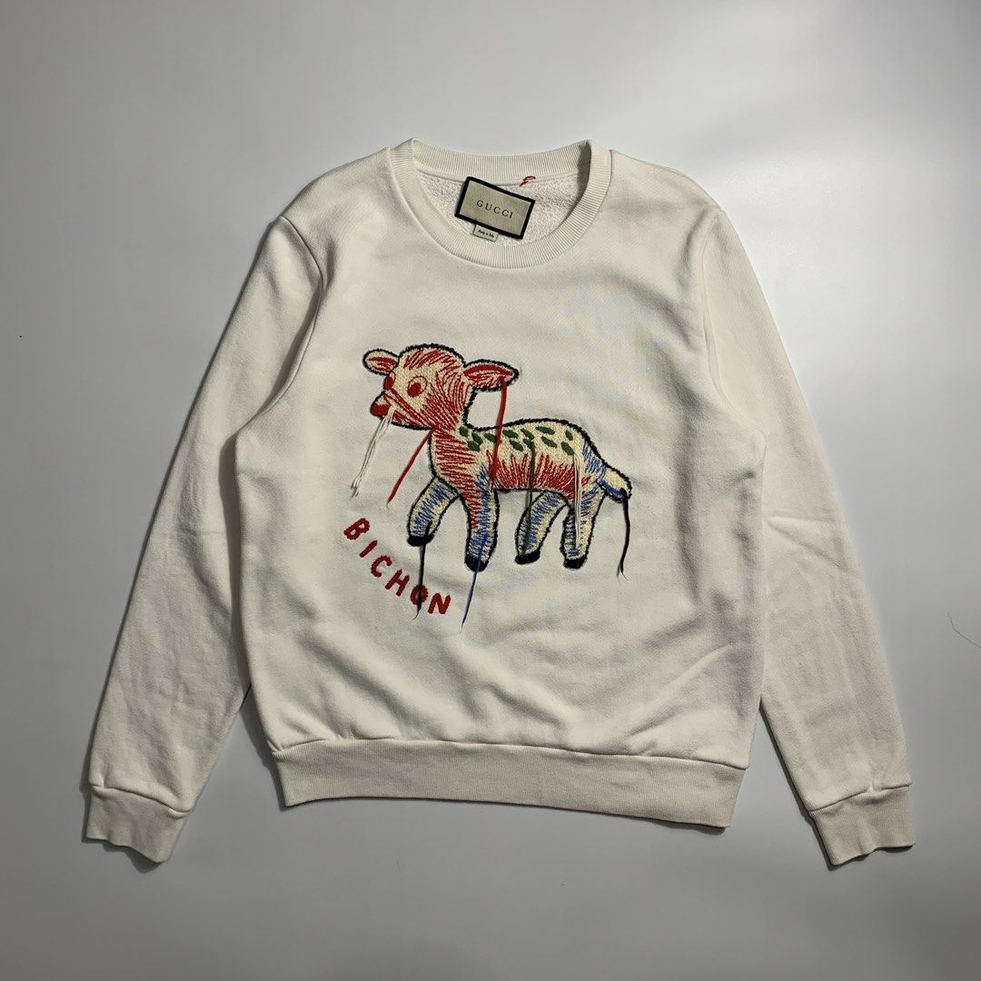 Gucci Lamb Bichon Embroidered White Sweatshirt (Category: Luxury Apparel) located in Dagupan City. Submitted by source_ph (Listing ID 1470776453, Image 1). Description: Size: Small - Medium ‎Width : 21 ‎Length: 26 ‎Shoulder: 17 ‎Sleeves: 25.5 - Brand: Gucci - Style: Crewneck sweatshirt in off-white - Material: Heavyweight, clean cotton - Design: Large embroidered lamb graphic with multi-colored details and red 'BICHON' lettering - Details: Classi
