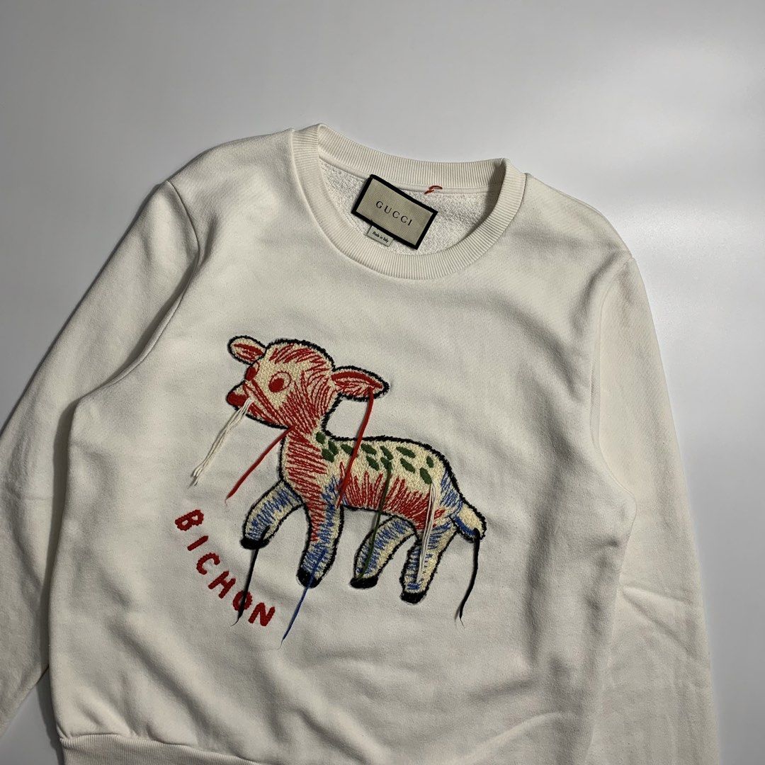 Gucci Lamb Bichon Embroidered White Sweatshirt (Category: Luxury Apparel) located in Dagupan City. Submitted by source_ph (Listing ID 1470776453, Image 2). Description: Size: Small - Medium ‎Width : 21 ‎Length: 26 ‎Shoulder: 17 ‎Sleeves: 25.5 - Brand: Gucci - Style: Crewneck sweatshirt in off-white - Material: Heavyweight, clean cotton - Design: Large embroidered lamb graphic with multi-colored details and red 'BICHON' lettering - Details: Classi