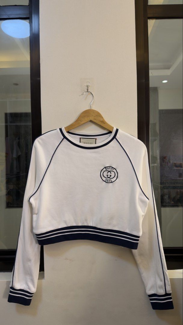 Gucci White Cropped Sweatshirt (Category: Coats, Jackets and Outerwear) located in Paranaque City. Submitted by preluxeshop_ph (Listing ID 1470800027, Image 2). Description: Gucci White Cropped Sweatshirt with Navy Ribbing - Features blue piping and striped ribbed cuffs and hem - Embroidered Gucci 1921 circle logo patch on the chest - Classic round neck and long raglan sleeves - Material: 100% premium cotton - Made in Italy - Stylish and comforta