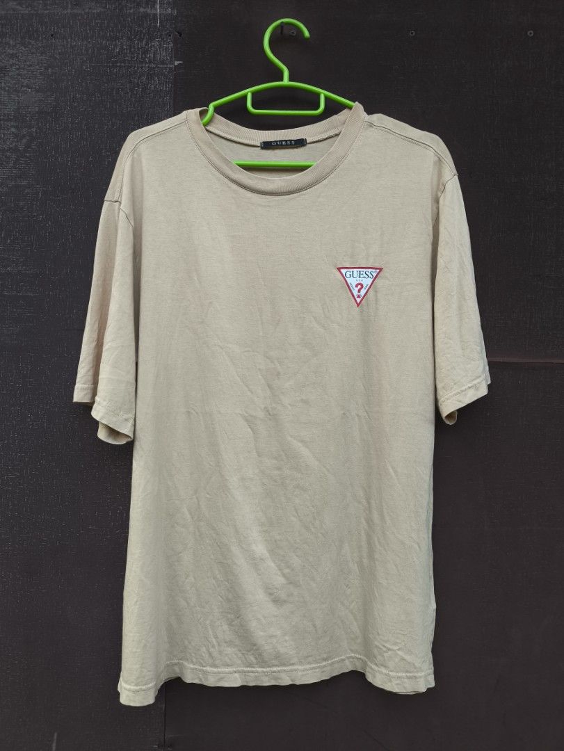 Guess Beige Logo T-Shirt Size M (Category: Tshirts & Polo Shirts ) located in Guiuan. Submitted by lazyflipthrift-14 (Listing ID 1470861343, Image 1). Description: - Brand: Guess - Color: Beige - Size: Medium (Tag size M, standard fit) - Material: 100% Cotton (Made in Vietnam) - Design: Small triangle logo patch on chest, crew neck, relaxed fit - Style Number: NL2K9361 - Condition: Clean fabric with minimal wear.