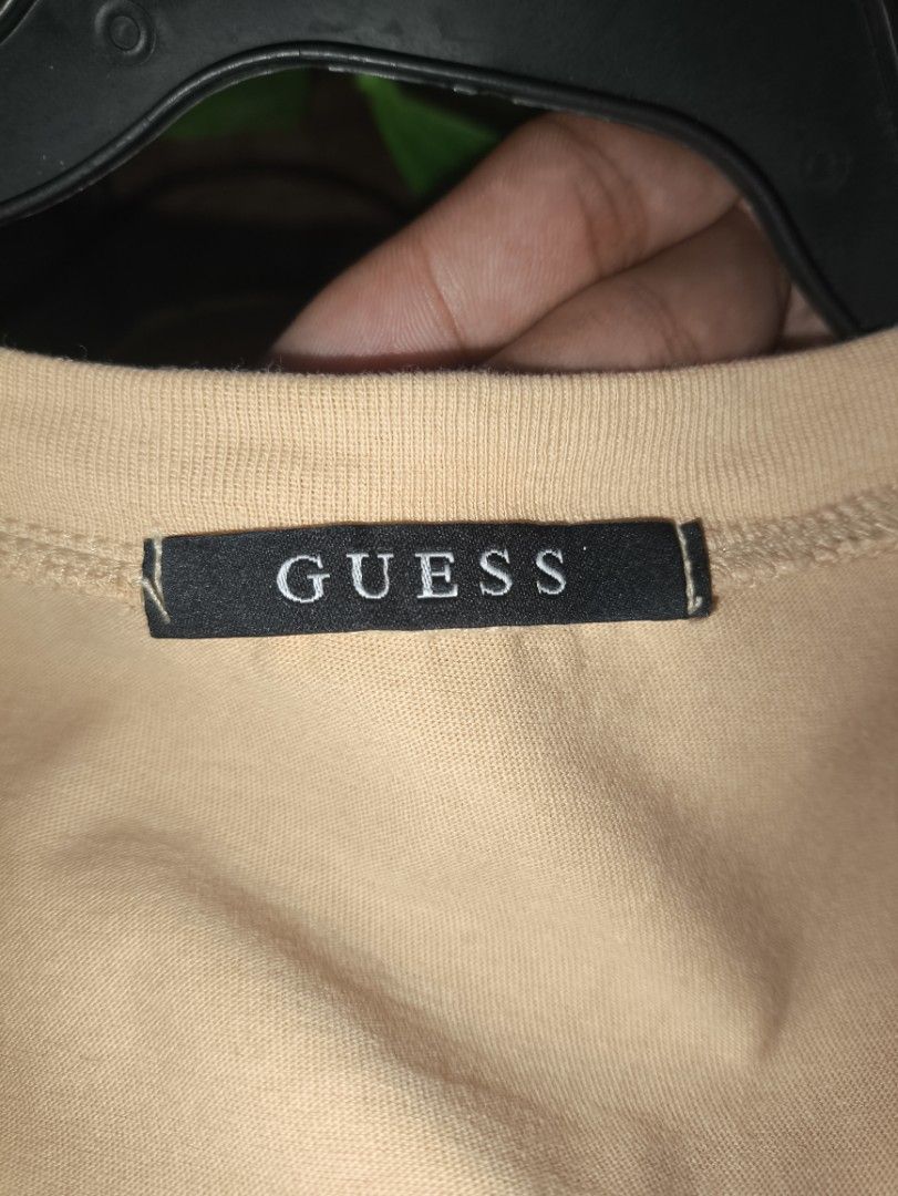 Guess Beige Logo T-Shirt Size M (Category: Tshirts & Polo Shirts ) located in Guiuan. Submitted by lazyflipthrift-14 (Listing ID 1470861343, Image 2). Description: - Brand: Guess - Color: Beige - Size: Medium (Tag size M, standard fit) - Material: 100% Cotton (Made in Vietnam) - Design: Small triangle logo patch on chest, crew neck, relaxed fit - Style Number: NL2K9361 - Condition: Clean fabric with minimal wear.