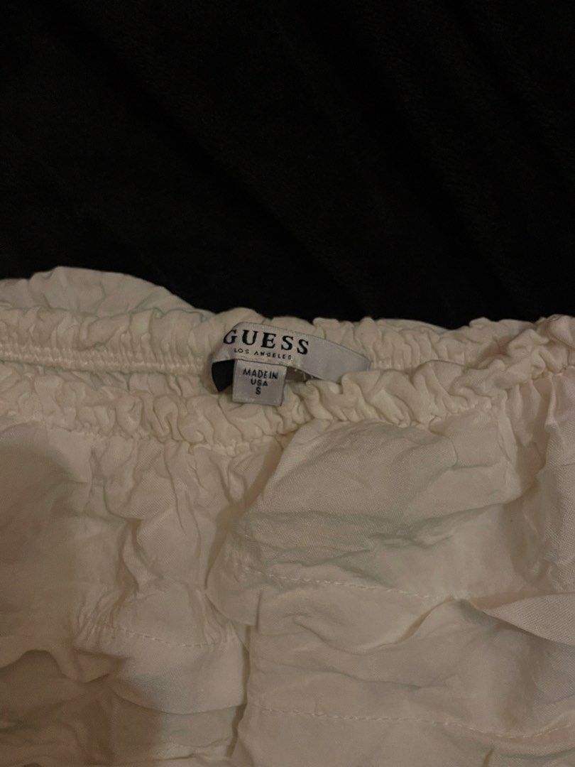 Guess Off-The-Shoulder Ruffle Top White Small (Category: Sleeveless) located in Bacolod City. Submitted by angelsantii (Listing ID 1470904750, Image 2). Description: - Brand: Guess Los Angeles - Size: Small - Color: White - Made in USA - Material: Super lightweight - Design: Off-the-shoulder, layered chest ruffles, short sleeves, smocked stretchy bodice, and ruffled hem - Styling: Easy to dress up with jeans or a skirt.