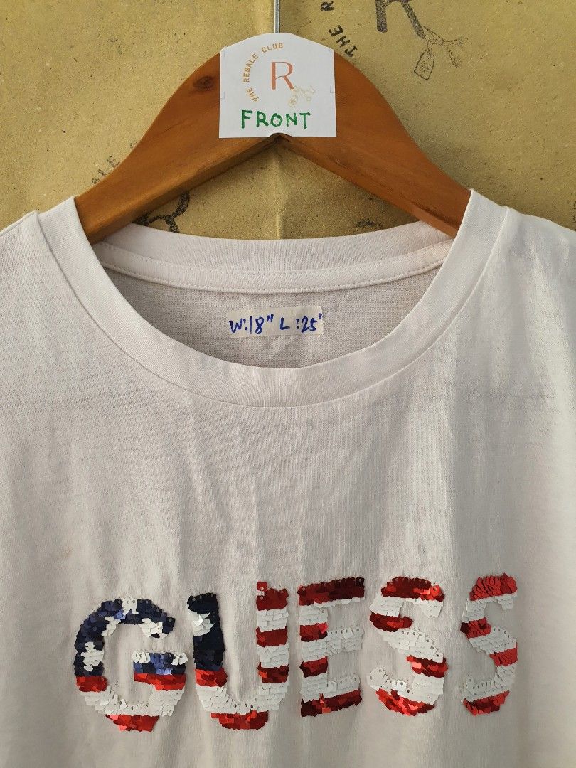 GUESS White Sequin Logo T-shirt (Category: Shirts) located in Tarlac. Submitted by resaleclub (Listing ID 1470849962, Image 2). Description: - Brand: GUESS - Color: Solid white with red, white, and blue sequin logo lettering on the front - Style: Short sleeve, casual crew neck, standard fit - Measurements: Width 18 inches, Length 25 inches - Condition: Clean and well-maintained - Versatile piece, perfect for pairing with denim or shorts - please 