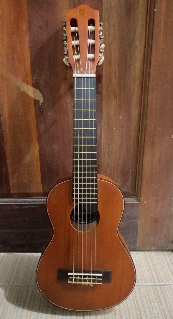 Guitale Guitarlele Classic Brown Mini Guitar (Category: Musical Instruments) located in Mandaluyong City. Submitted by kinergy04 (Listing ID 1470894861, Image 1). Description: - Guitalele Mini Classical Guitar - Color/Finish: Natural brown wooden finish - Hardware & Strings: Nylon strings with a classic slotted headstock - Design: Compact body shape, ideal for travel and practice on the go - Condition: Plays fine; note there is one small ding nea